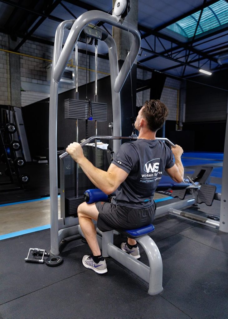 Man traint met lat pulldown machine in sportschool.